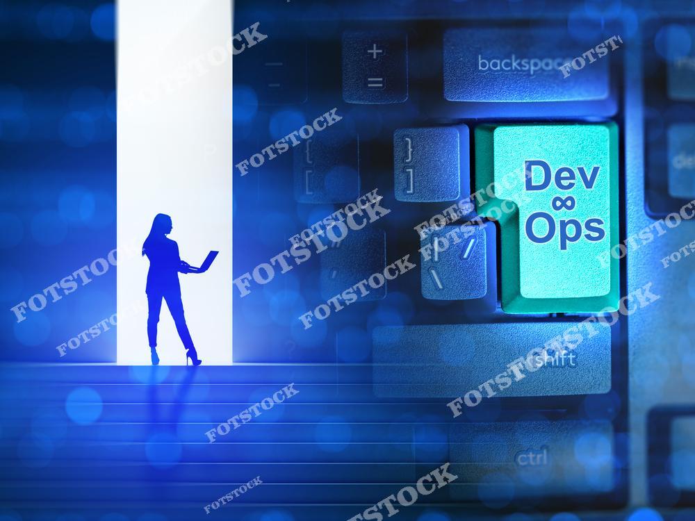 На фотографии изображена клавиатура с подсвеченной клавишей "DevOps" и силуэт человека с ноутбуком. Снимок символизирует современные подходы к автоматизации и интеграции процессов в сфере разработки и эксплуатации IT-систем. Это отражает ключевую роль DevOps в обеспечении гибкости и эффективности технологий.