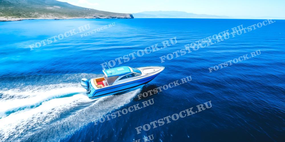 На фотографии изображена быстроходная лодка, скользящая по ярко-синему морю. На заднем плане виднеется береговая линия с холмами и горами. Лодка оставляет за собой белую пену на воде, создавая ощущение скорости и динамики. Эта фотография может быть использована для иллюстрации материалов о морских путешествиях, яхтинге, а также в рекламных кампаниях туристических агентств и производителей яхт и катеров.