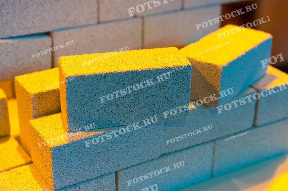 Фотография представляет собой стопку пеноблоков с характерной пористой структурой, которая придаёт материалу легкость и отличные теплоизоляционные свойства. Это изображение идеально подходит для иллюстрации строительных и ремонтных процессов, а также для использования в статьях о современных строительных материалах. Оно будет полезным в рекламных материалах компаний, занимающихся производством и продажей пеноблоков, демонстрируя их преимущества и особенности.