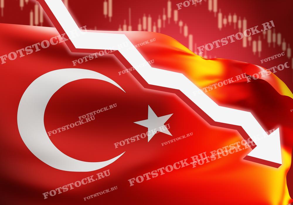 Фотография показывает флаг Турции на фоне графика, демонстрирующего резкое падение. Это изображение символизирует экономический спад или кризис в стране.