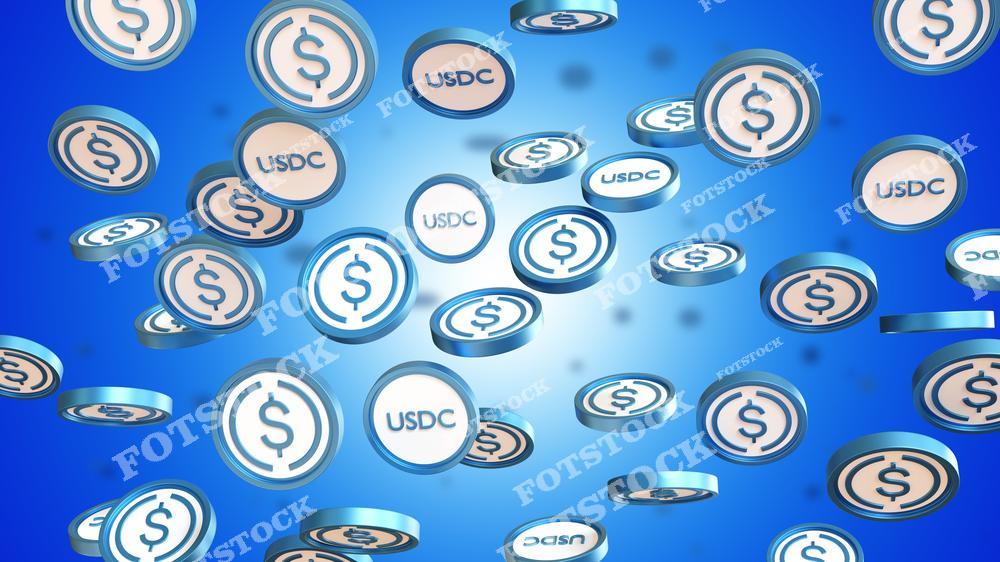 На изображении множество монет с символом USD Coin, парящих на синем фоне. Динамичный фон создает ощущение движения и масштабности. Фото ассоциируется с цифровыми финансами, криптовалютами и инновациями.