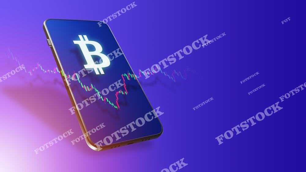 На изображении показан смартфон с символом биткоина на экране, на фоне отображается график колебаний цен. Фотография отражает мир криптовалют и цифровых финансовых технологий. Это подчёркивает современные инвестиционные возможности и интерес к криптовалютам.