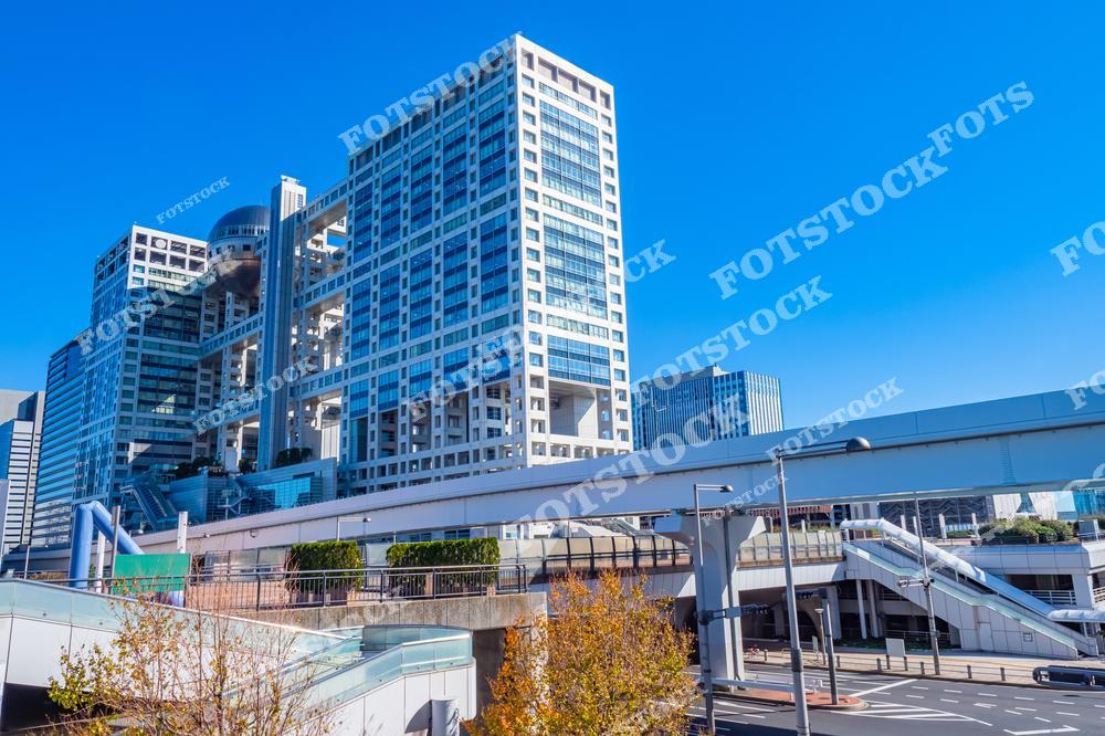 На фотографии изображено здание Fuji TV, расположенное на острове Одайба в Токио. Это здание известно своим уникальным дизайном с большой сферой, встроенной в верхнюю часть конструкции. Одайба — популярный район, привлекающий туристов современными зданиями, торговыми центрами и красивыми видами на Токийский залив. Сочетание современного дизайна и функциональности делает здание одной из самых узнаваемых достопримечательностей города. Это место символизирует динамичность и высокие технологии, характерные для японской столицы.