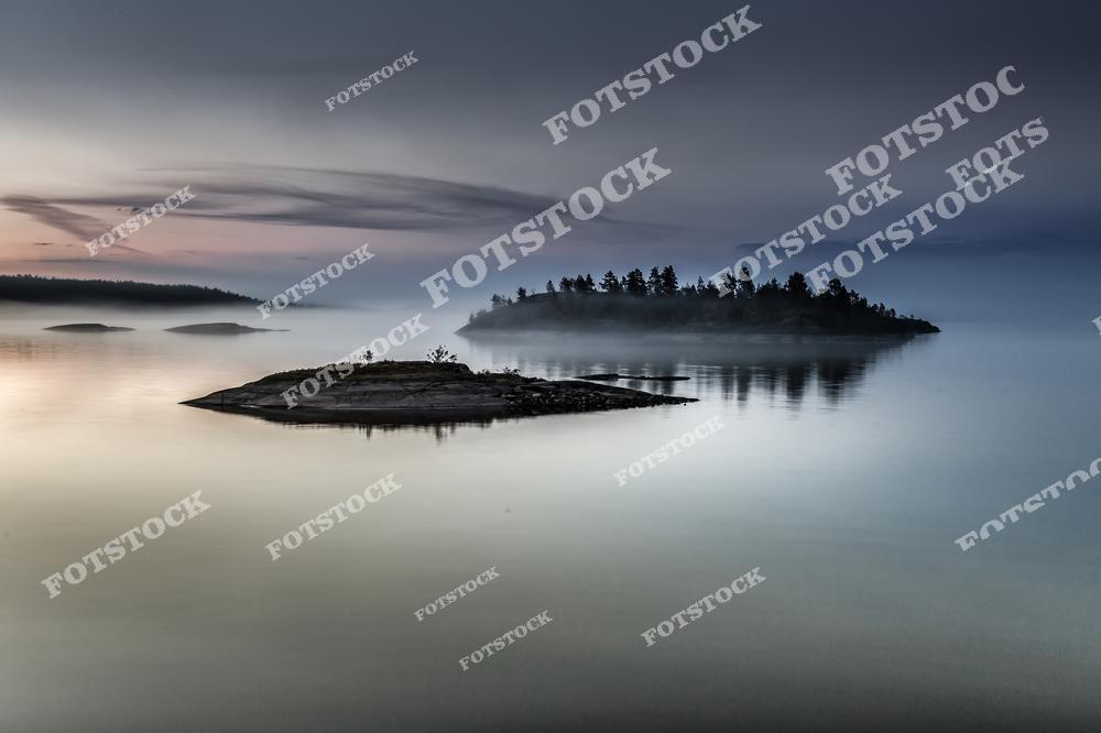 Фотография запечатлела загадочную атмосферу Ладожских шхер на рассвете. Вода, словно зеркало, отражает утреннее небо и силуэты островов. Туман окутывает деревья, создавая ощущение уединенности и мистики. Это место демонстрирует величие и спокойствие карельской природы, наполняя пространство тишиной и безмятежностью.