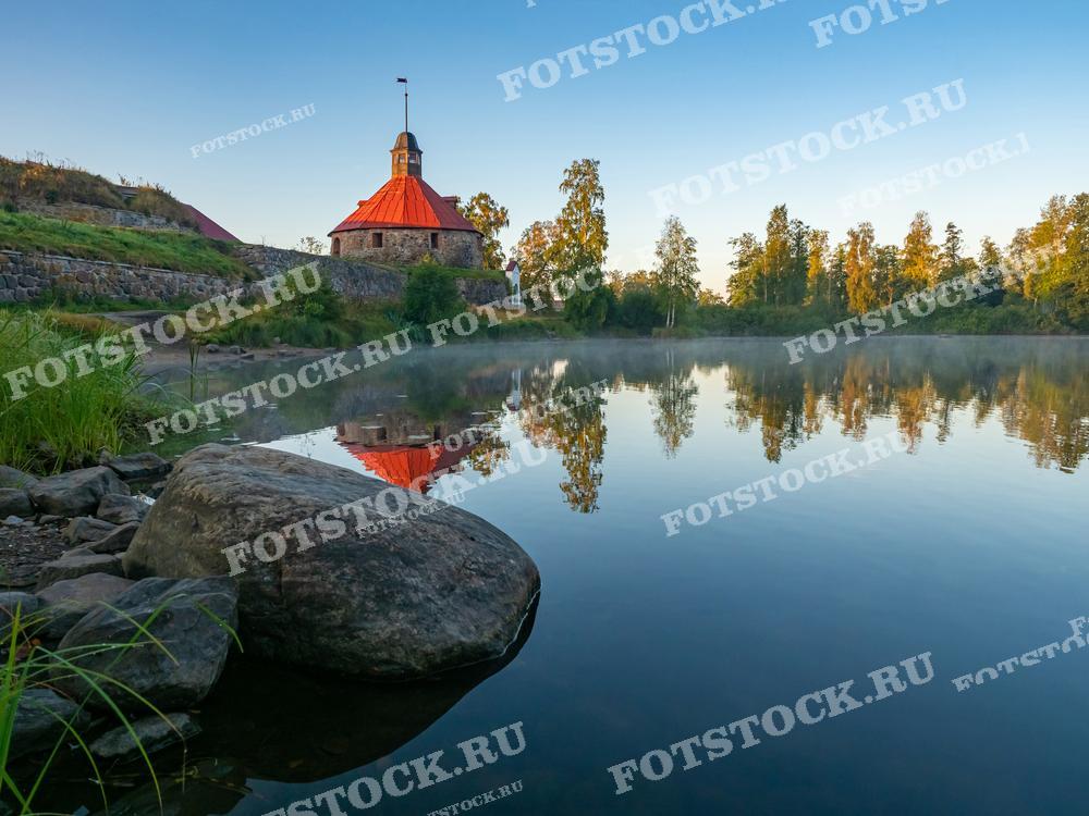 На фотографии изображена Корела - крепость, расположенная в Приозерске, Карелия. Окружающая природа и отсутствие ветра создают зеркальное отражение, что делает изображение особенно привлекательным для фотографии. Эта крепость является популярным туристическим объектом и может использоваться для иллюстрации путеводителей, исторических статей или образовательных материалов о Карелии.