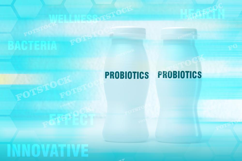 На изображении две бутылки с надписью "PROBIOTICS" на переднем плане, на фоне схематических изображений бактерий и гексагональных элементов, ассоциируемых с наукой и инновациями. Фотография может использоваться для рекламы и обучающих материалов, связанных с продвижением здорового образа жизни, питания и использования пробиотических добавок для поддержания здоровья кишечника и иммунитета.