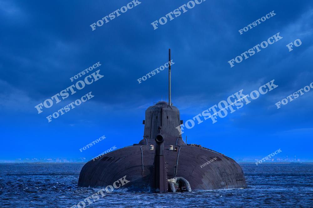 На фотографии изображена подводная лодка, движущаяся по поверхности воды под тёмным грозовым небом. Драматическое освещение подчеркивает внушительный силуэт судна и его стратегическое значение. Снимок символизирует современные технологии военно-морского флота и мощь защиты.