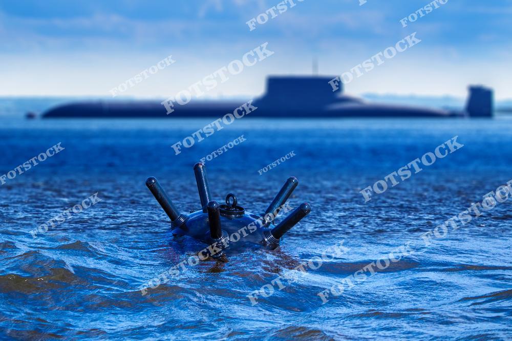 На переднем плане изображена морская мина, находящаяся в воде, на заднем плане видна подводная лодка. Снимок подчеркивает стратегическую важность подводной обороны и потенциальные угрозы для морского судоходства. Фотография отражает военно-морскую мощь и защиту водных территорий.