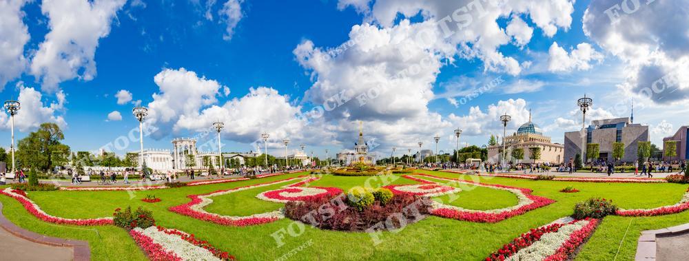 На фотографии представлена панорамная композиция с цветочными клумбами на ВДНХ в Москве. Яркие узоры из цветов украшают центральную аллею выставочного комплекса.