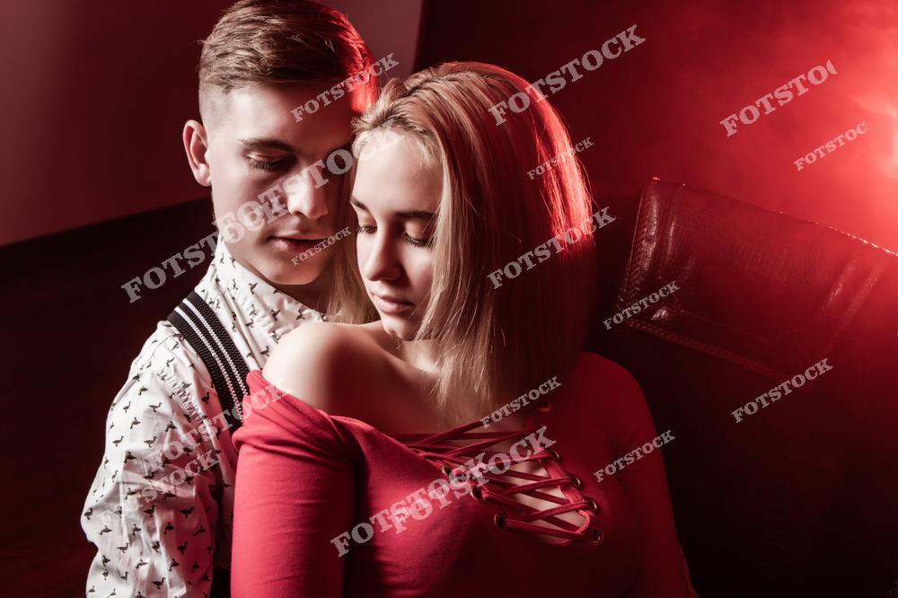 На фотографии изображена пара, передающая страстные и романтичные чувства друг к другу. Мужчина очарован присутствием девушки, что отражается в его взгляде. Сцена символизирует интимные отношения, сексуальное притяжение и глубину чувств между влюбленными.