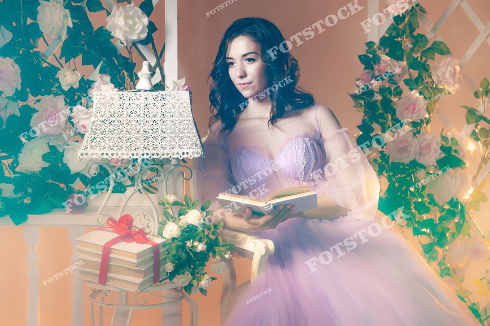 Фотоснимок показывает девушку-модель в розовом платье, читающую книгу на фоне цветущих роз, где изображение передаёт атмосферу спокойствия и романтики в розовом саду. Эта фотография выглядит как нежная иллюстрация, а картинка соединяет книги, цветы и задумчивый образ, создавая выразительный и поэтичный слайд чтения на природе.