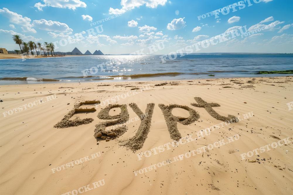 На фотографии изображен пляж с надписью "Egypt", написанной на песке, на фоне пирамид и пальм. Вдалеке видны пирамиды Гизы, а солнечный свет отражается в водах реки. Сцена передает атмосферу отдыха, туризма и красоты египетского пейзажа.