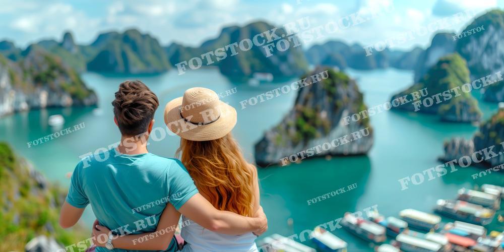 На фотографии изображена пара, обнимающаяся и любующаяся живописным видом на залив Халонг с лодками и островами во Вьетнаме. Яркий солнечный день, голубая вода и зелёные острова создают атмосферу романтики и умиротворения. Этот снимок подчеркивает красоту совместных путешествий и отдыха на природе во Вьетнаме.